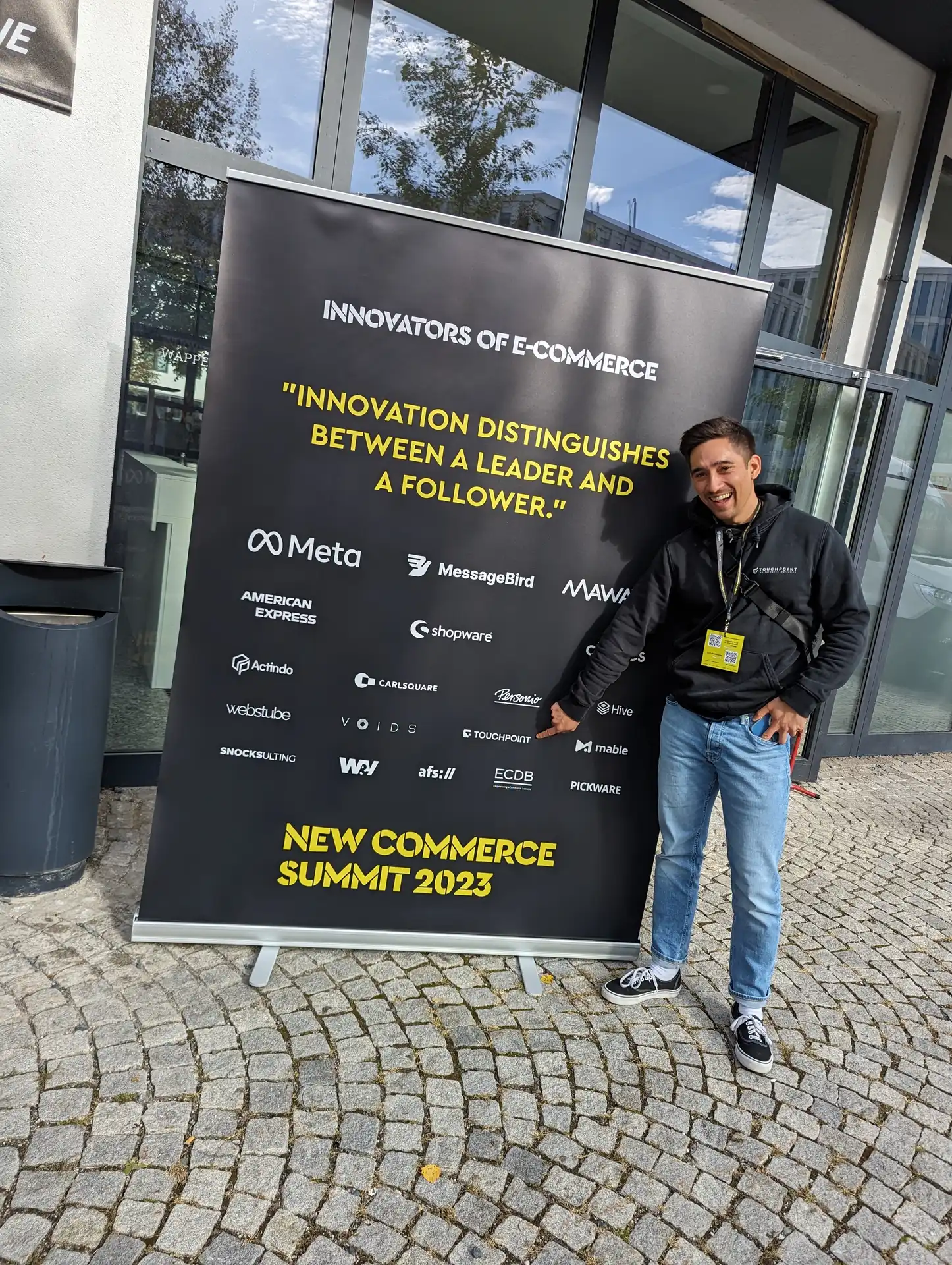Kollege vor dem Banner des New Commerce Summit 2023.