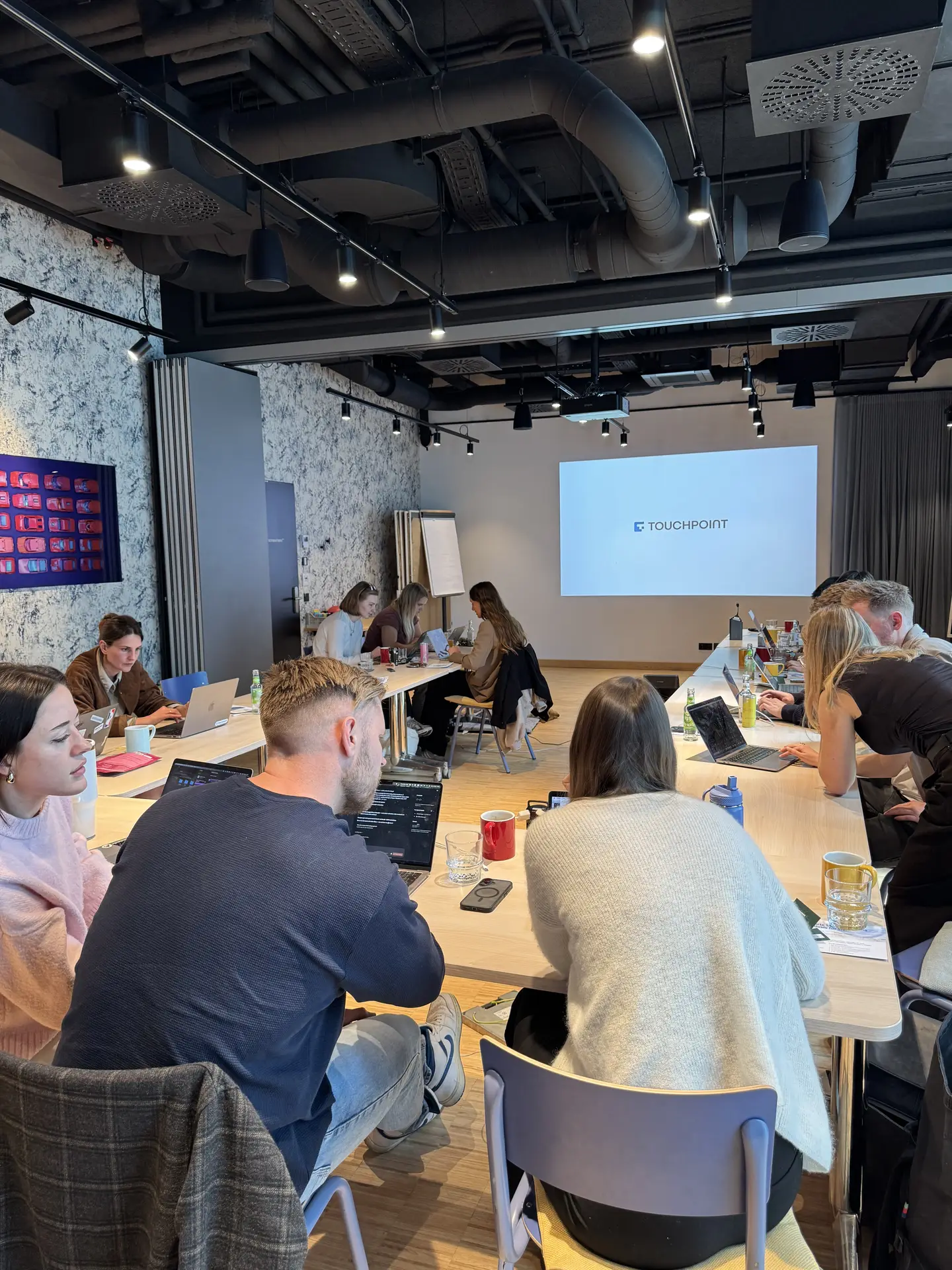 Kolleginnen und Kollegen arbeiten im Workshop an Laptops, auf der Leinwand läuft ein Vortrag.