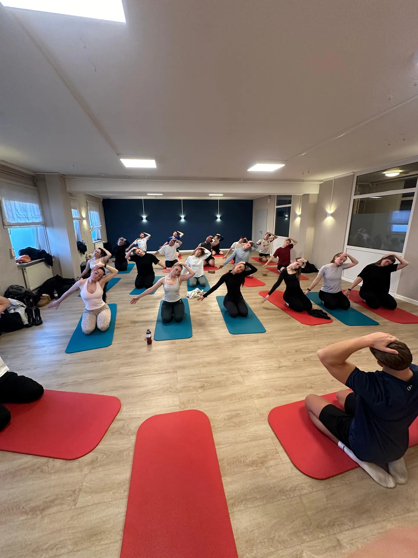Sportkurs im Büro: das Team auf roten und blauen Matten in Reihen.