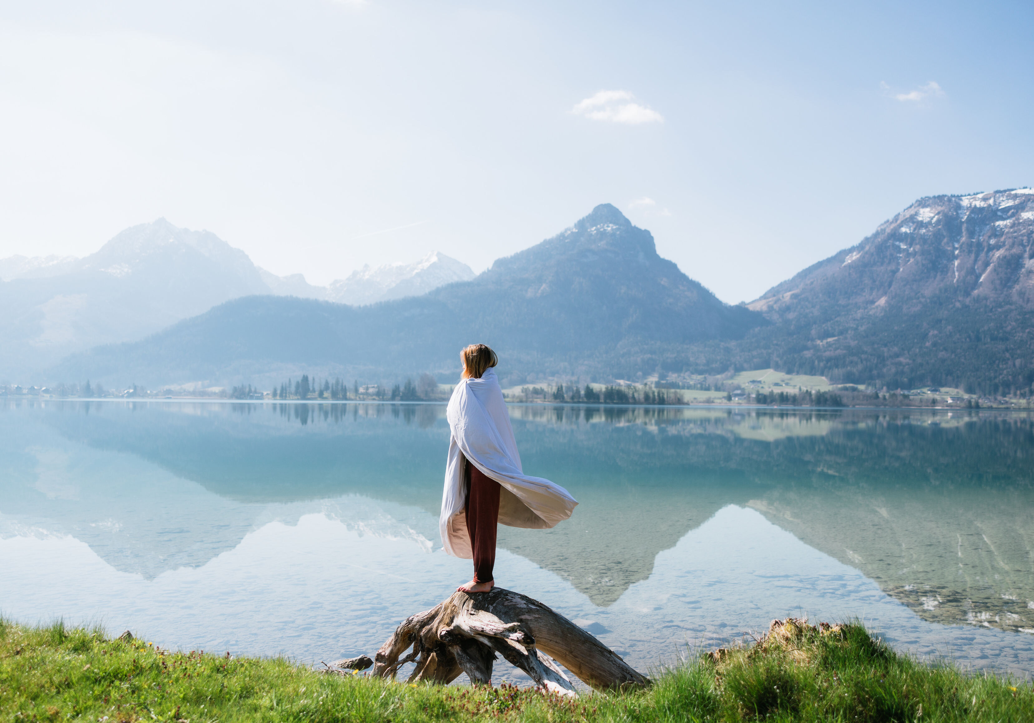 Frau in eine BLACKROLL-Recovery-Decke gehüllt an einem Alpensee.