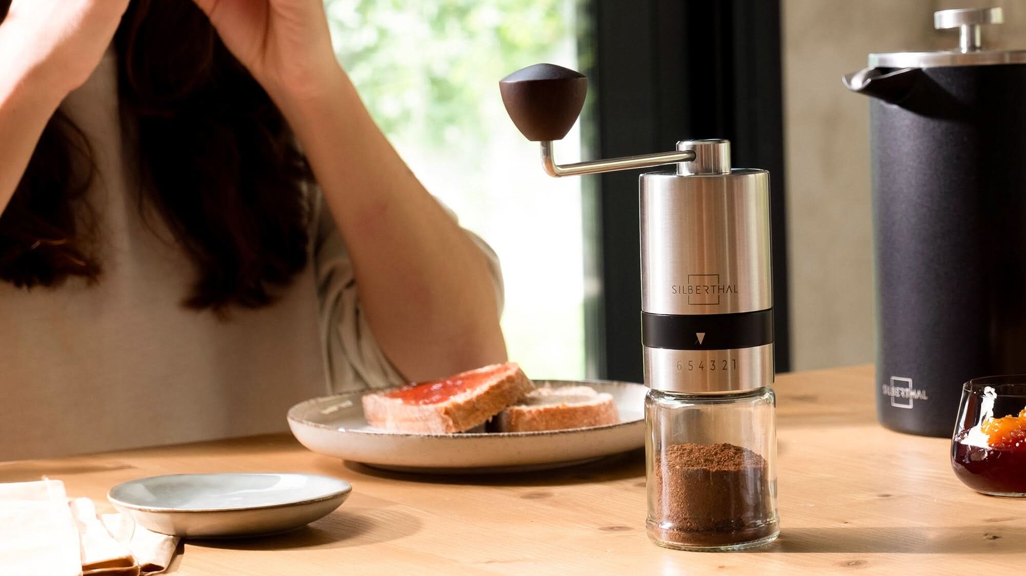 Frühstückstisch mit Silberthal-Kaffeemühle und Tellern.