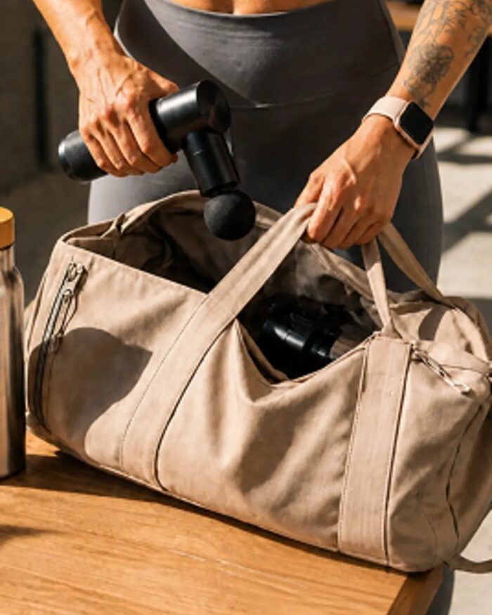 BLACKROLL, Hand verstaut eine BLACKROLL-Massagepistole in einer Sporttasche