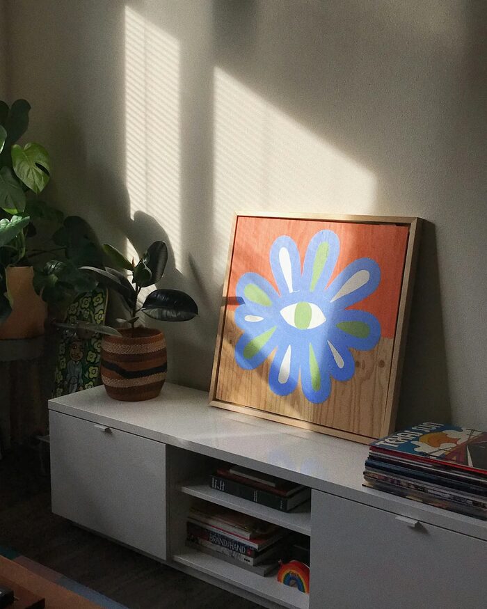 NewShades, Wohnraum mit Sideboard, Pflanzen und Kunstdruck in warmem Tageslicht