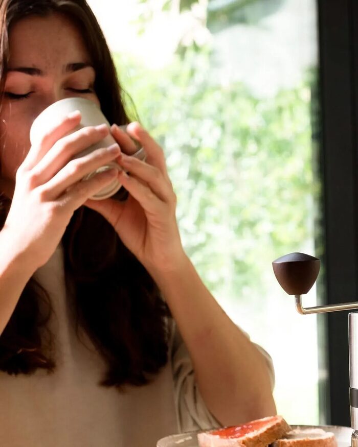 Silberthal, Frau trinkt am Frühstückstisch Kaffee, daneben eine Handkaffeemühle