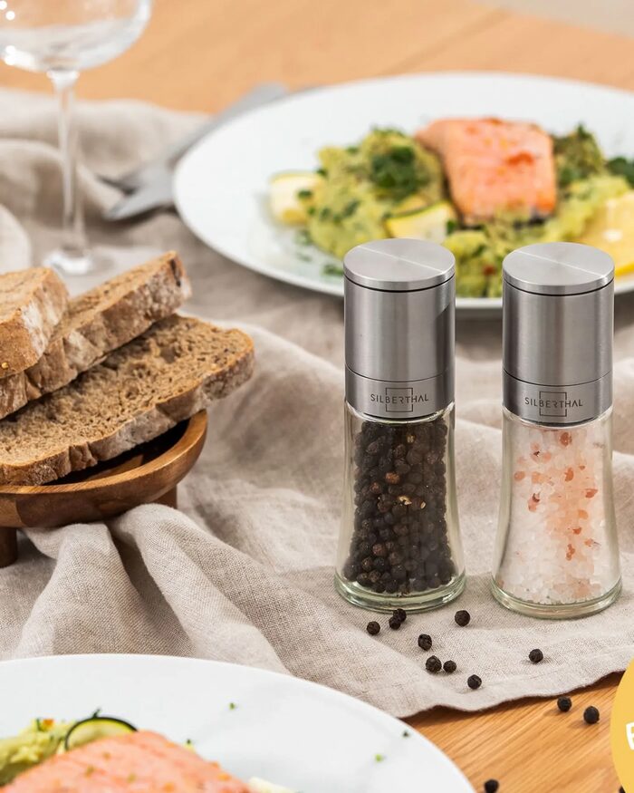 Silberthal, Gedeckter Holztisch mit Lachsgerichten, Brot und zwei Gewürzmühlen auf Leinen