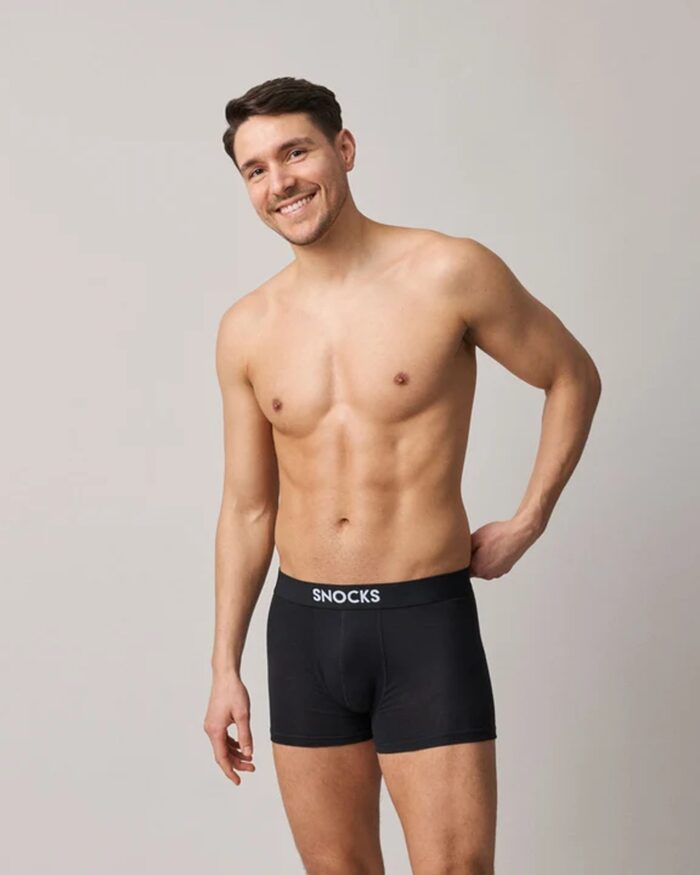 Snocks, Mann in einer schwarzen Boxershorts von Snocks vor hellgrauem Grund