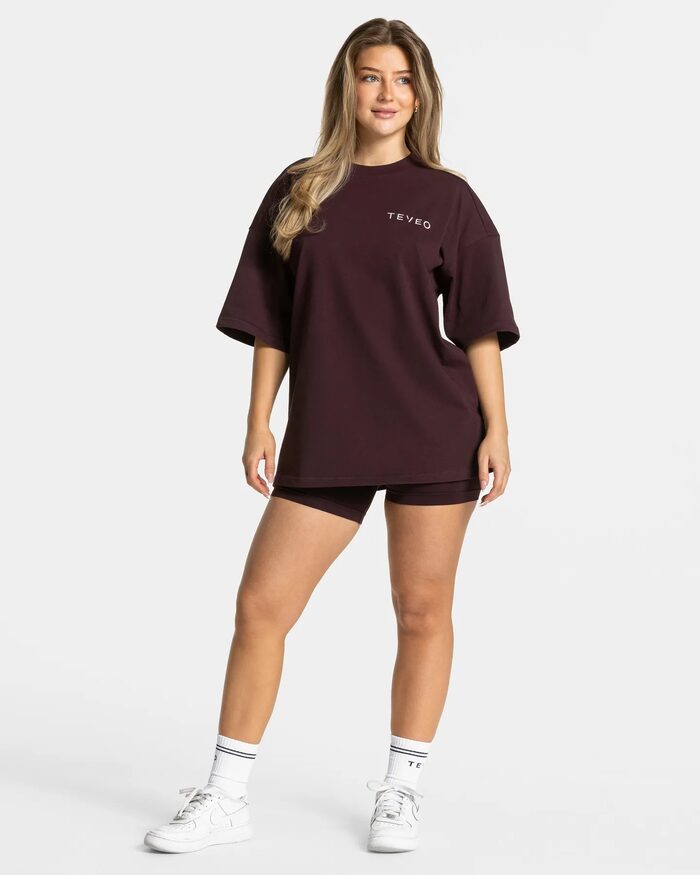 TEVEO, Frau in weinrotem Oversized-Shirt und Radlerhose, Ganzkörperaufnahme