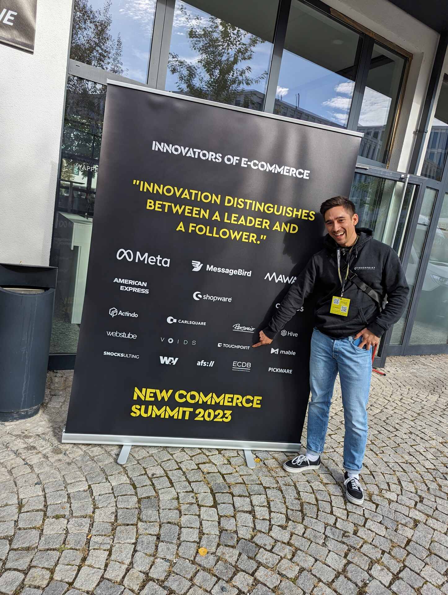 Kollege vor dem Banner des New Commerce Summit 2023.