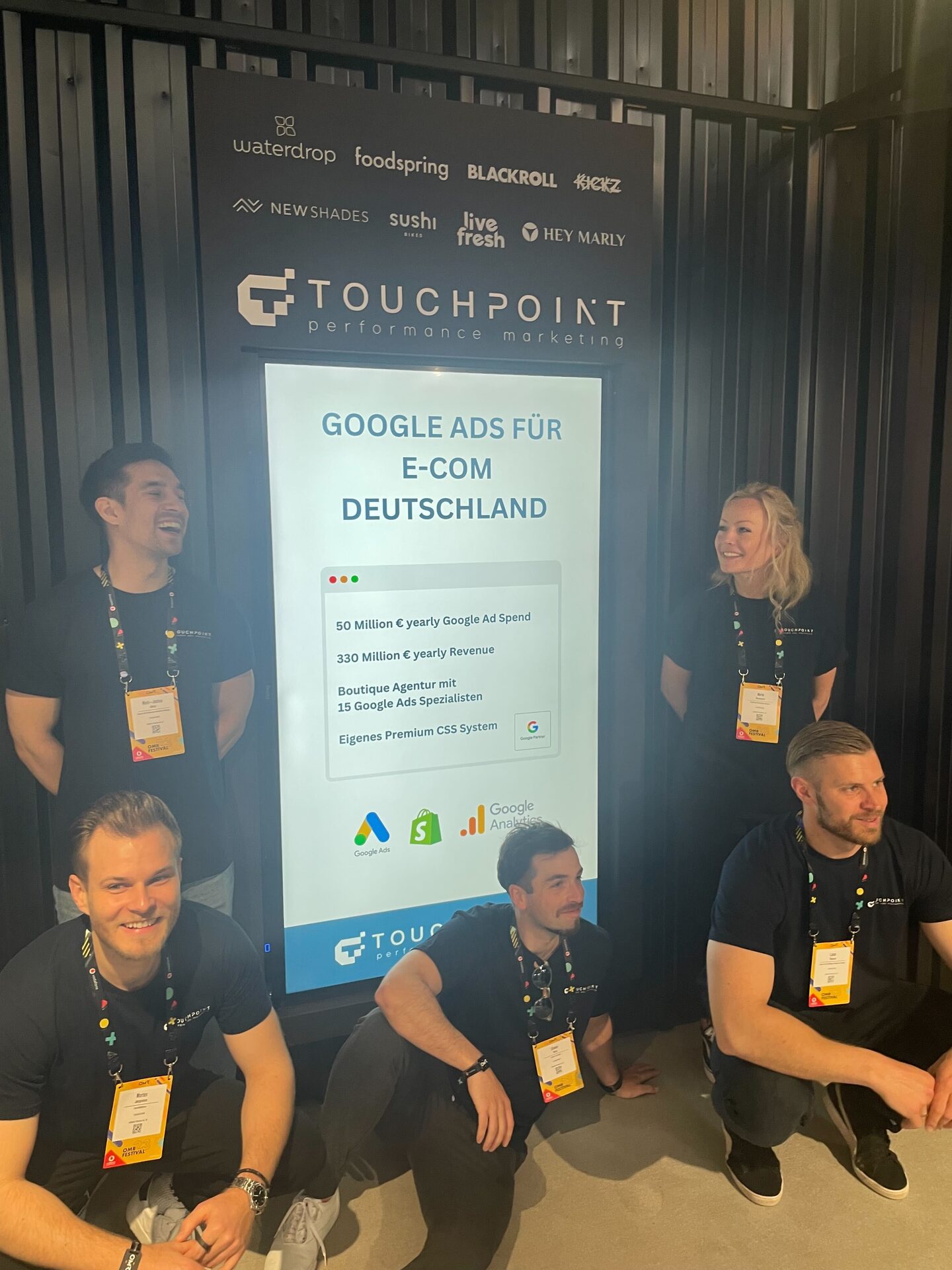 Vier Touchpoint-Kolleg:innen am Messestand vor der Wand „Google Ads für E-Com Deutschland“.