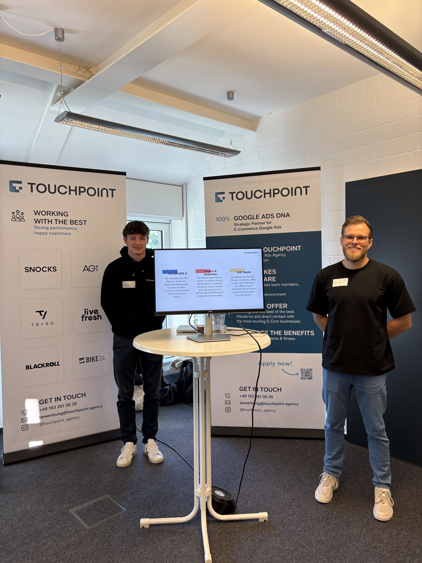 Zwei Touchpoint-Kollegen am Messestand neben dem Stehtisch mit Monitor.