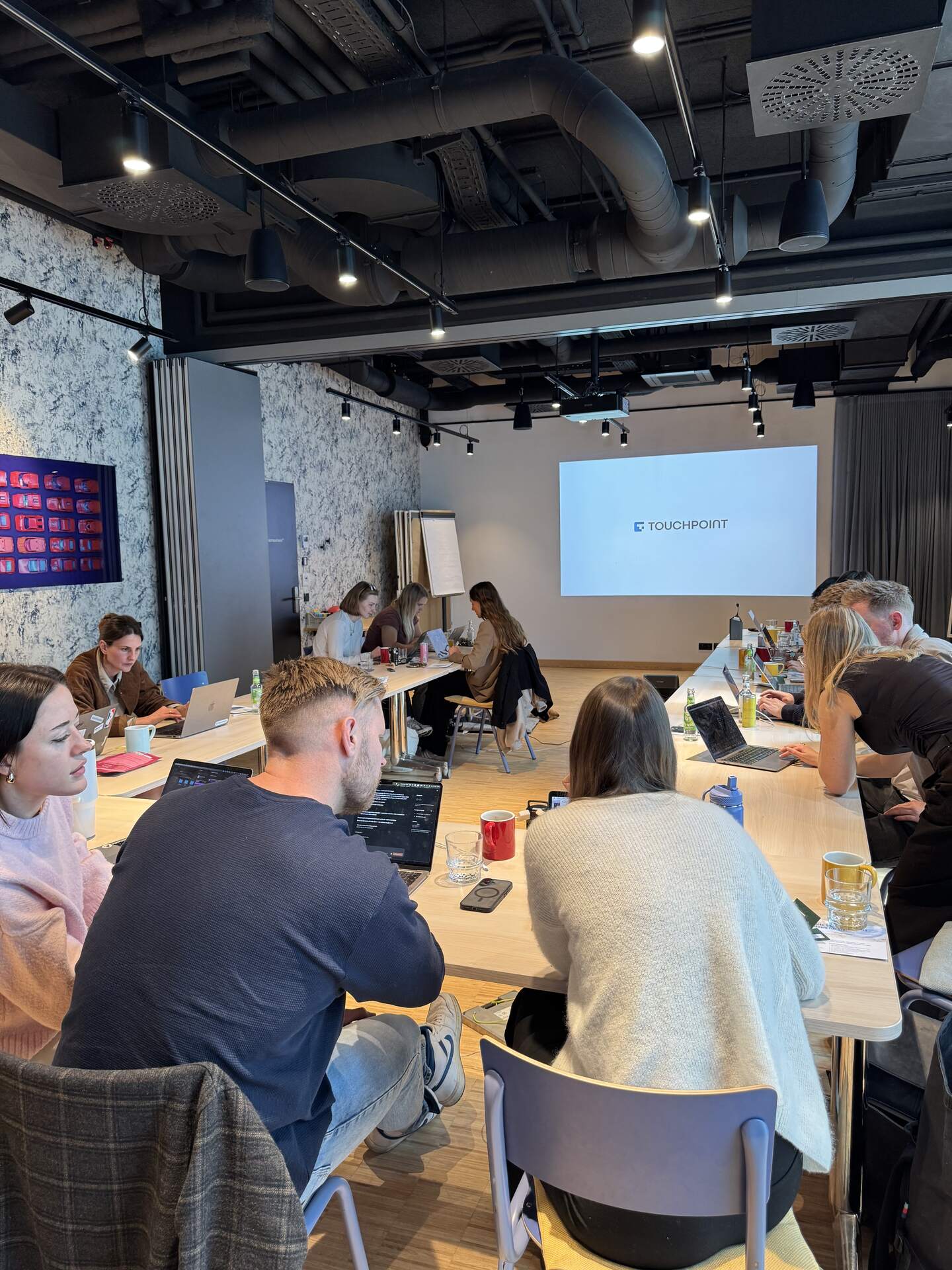 Kolleginnen und Kollegen arbeiten im Workshop an Laptops, auf der Leinwand läuft ein Vortrag.