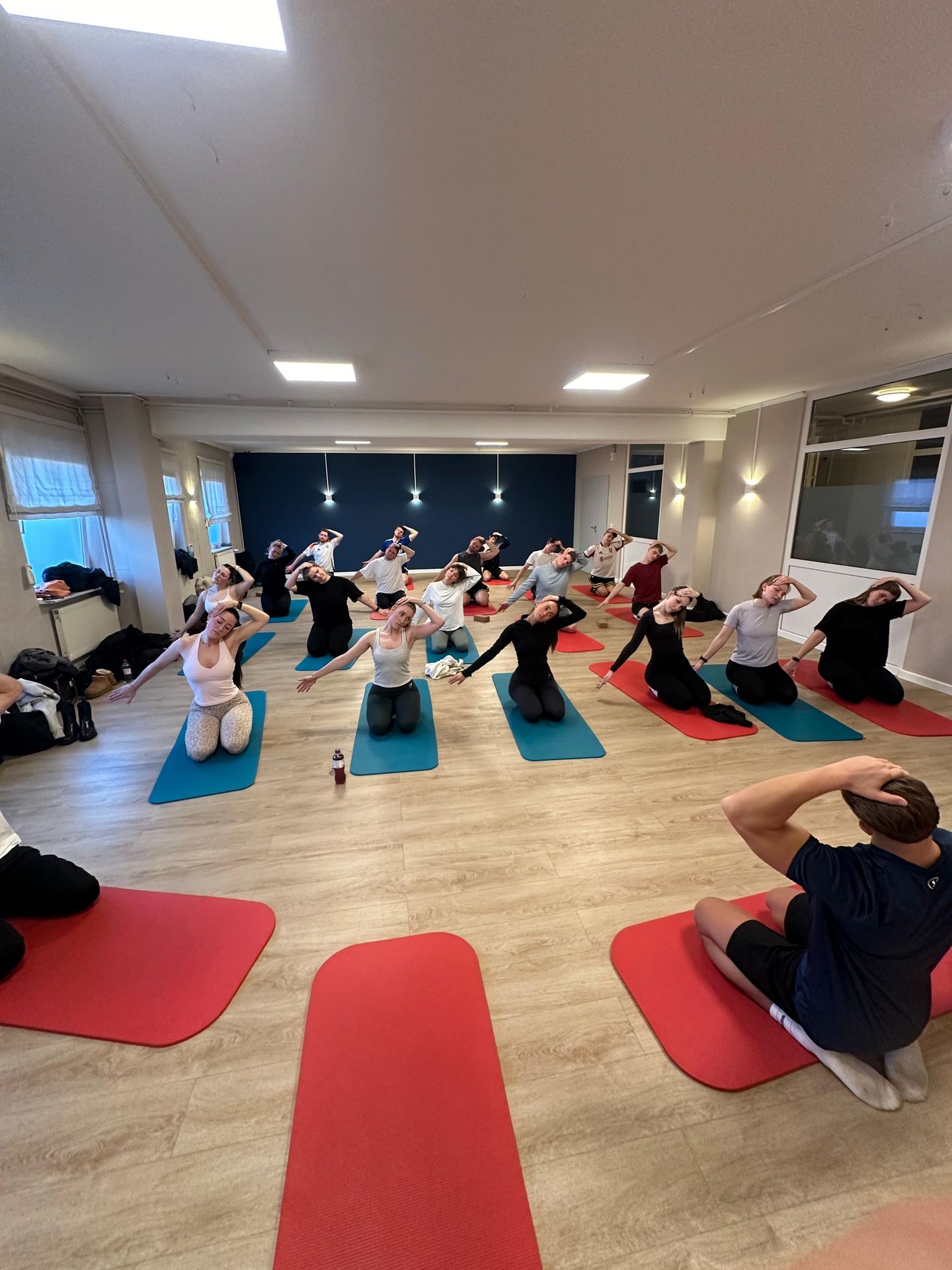 A sports class in the office: the team in rows on red and blue mats.